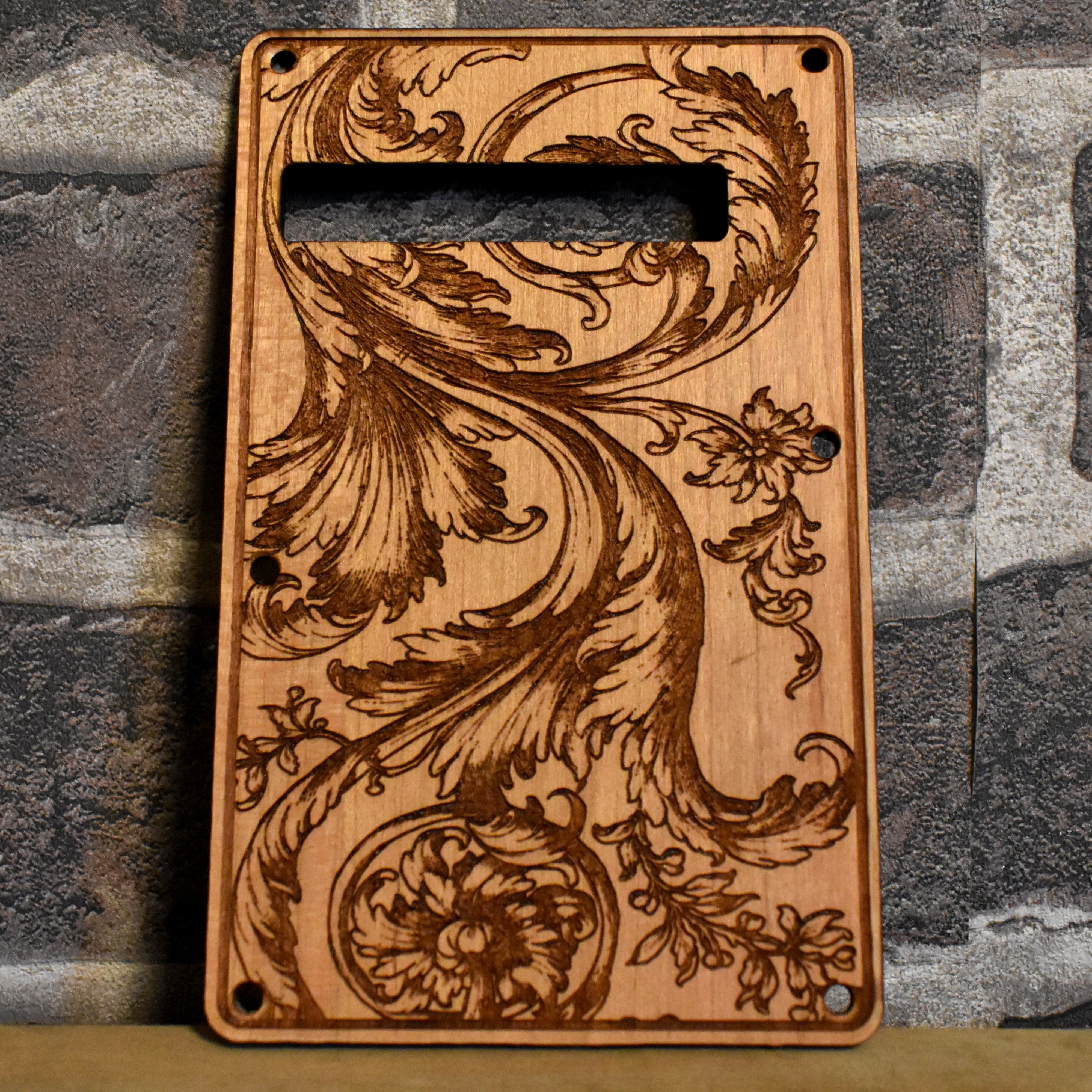 Floral tremolo cover for Stratocaster electric guitar, laser-engraved wood design.