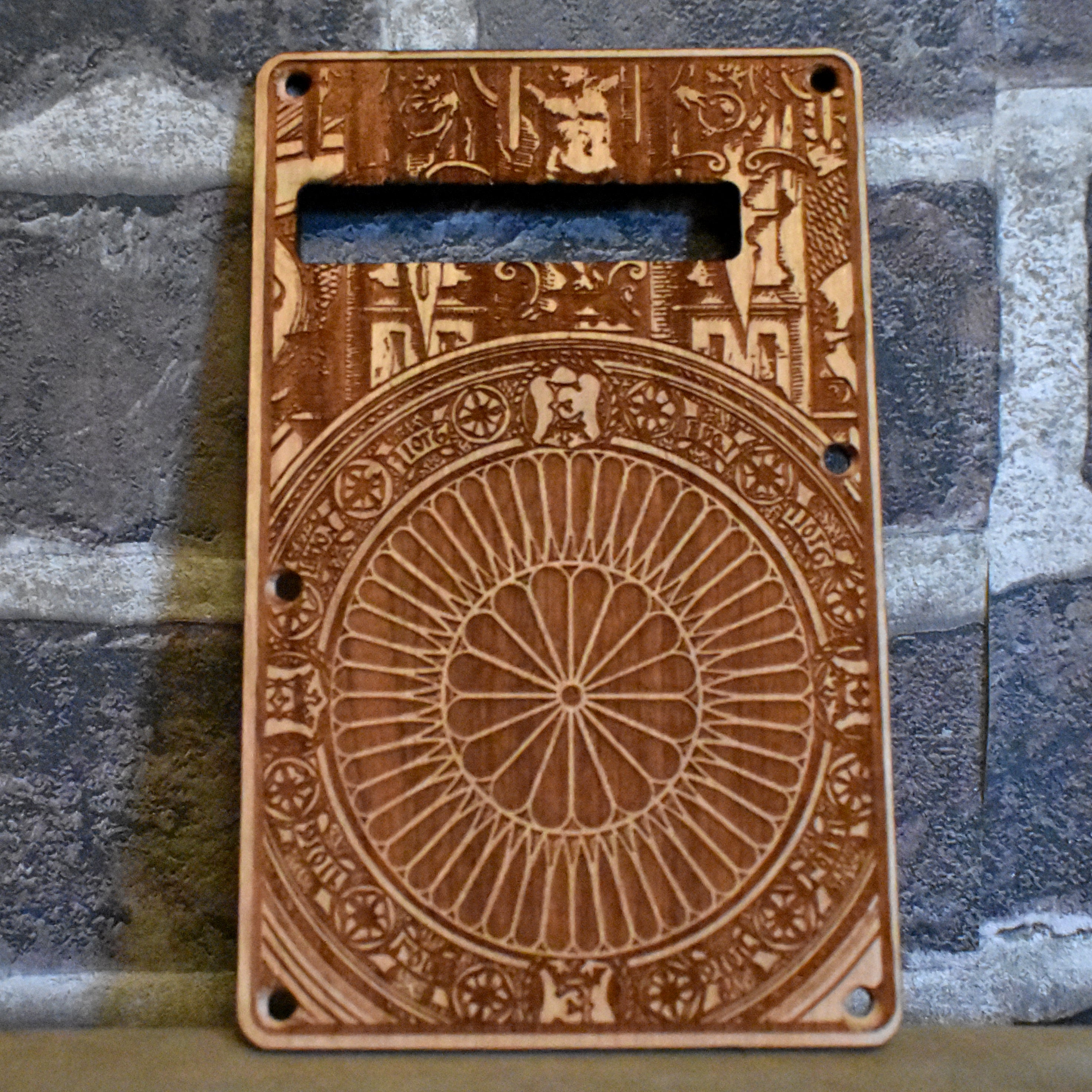 Cherry wood tremolo cover with laser-engraved Gothic embellishment design, custom fit for Fender Stratocaster.