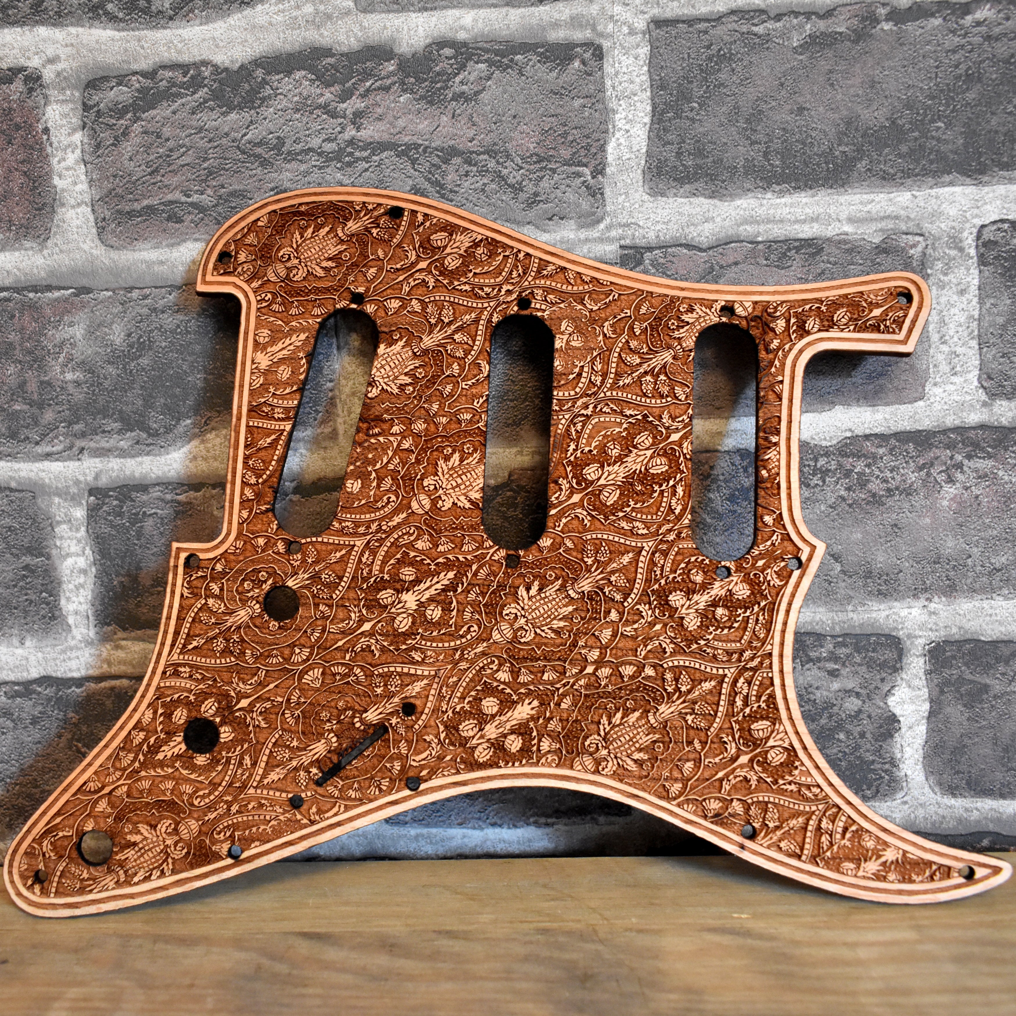 Fender Stratocaster cherry wood pickguard with laser-engraved flourish design, handcrafted for SSS & HSS guitars