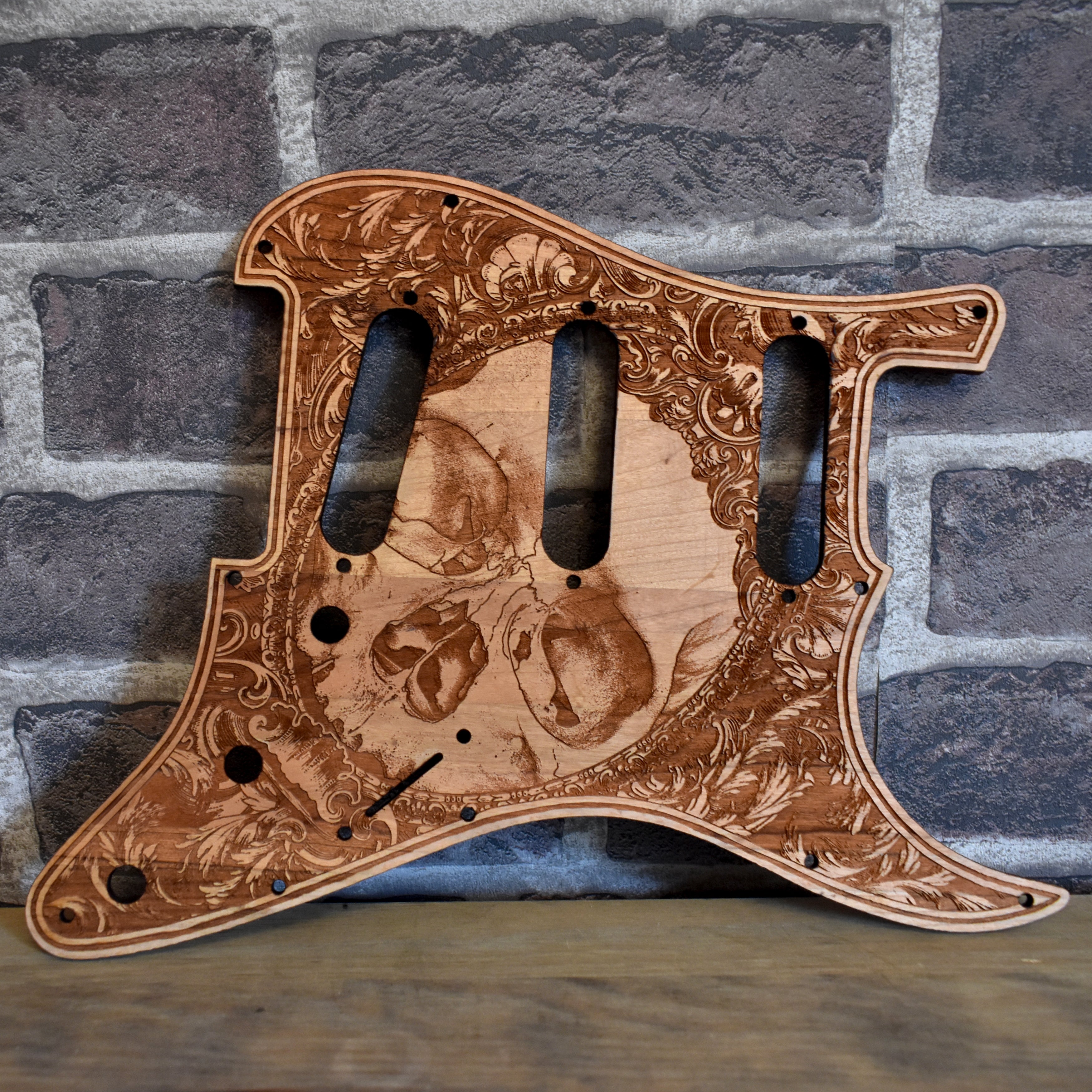 Fender Stratocaster cherry wood pickguard with laser-engraved flourish design, handcrafted for a premium finish.