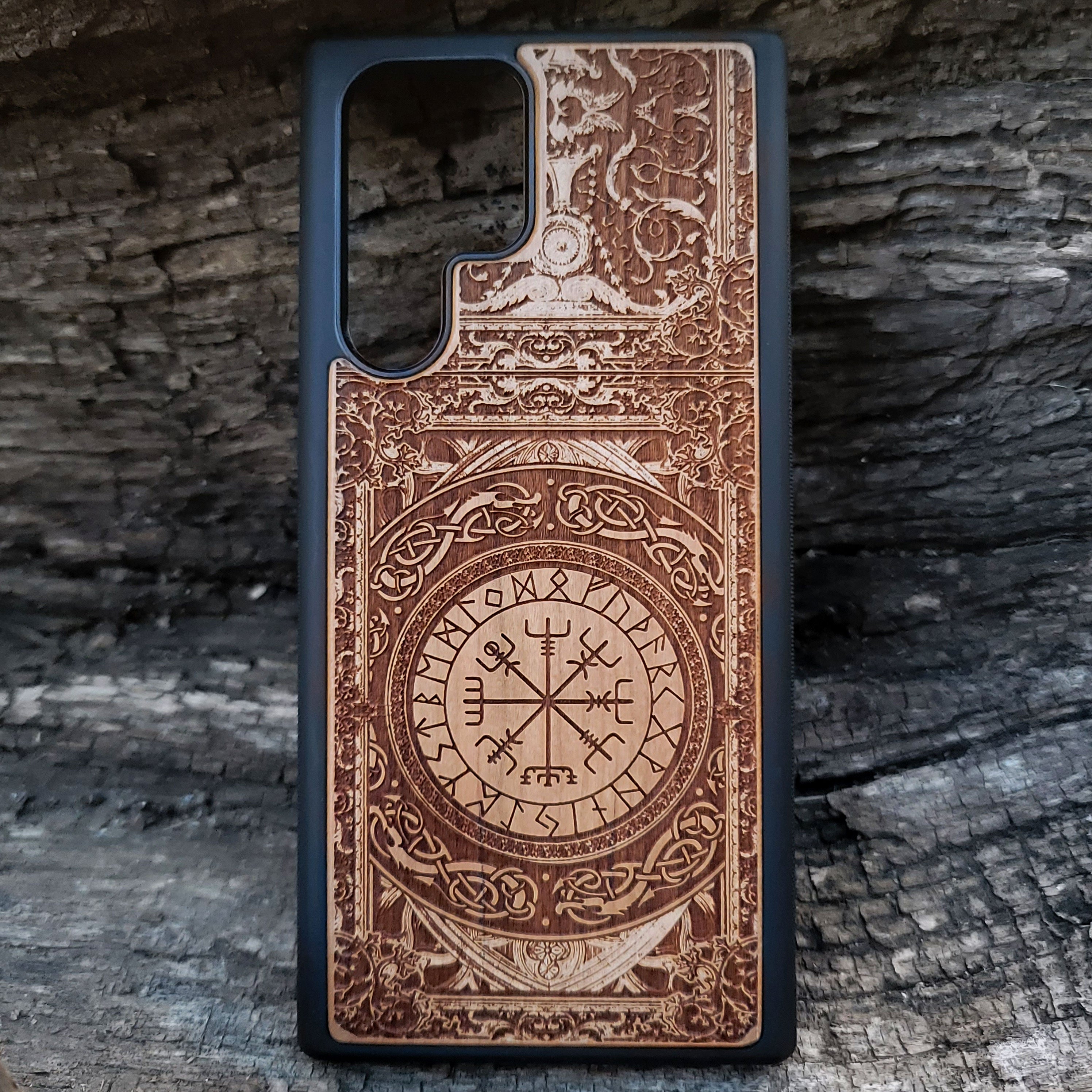 Viking-inspired wood phone case featuring the Vegvisir symbol surrounded by intricate Norse patterns and detailed engravings. Laser-engraved for durability and a unique design, this case is compatible with iPhone 16, 15, 14, 13, 12, 11, Pro Max, Mini, and Samsung Galaxy S25, S24, S23, S22, S21, S20 Ultra, Plus, Note 20. A perfect protective accessory for fans of Norse mythology and Viking culture.